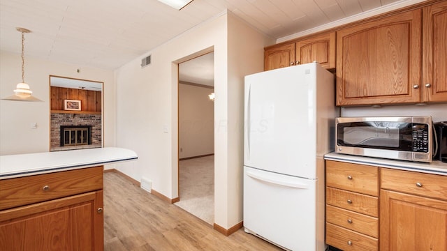 kitchen featuring light hardwood / wood-style floors, crown molding, a fireplace, white fridge, and hanging light fixtures