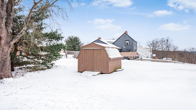 yard covered in snow featuring a storage shed