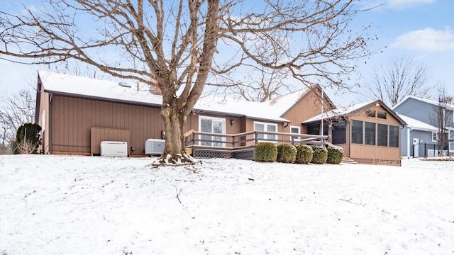 snow covered property featuring a sunroom and a wooden deck