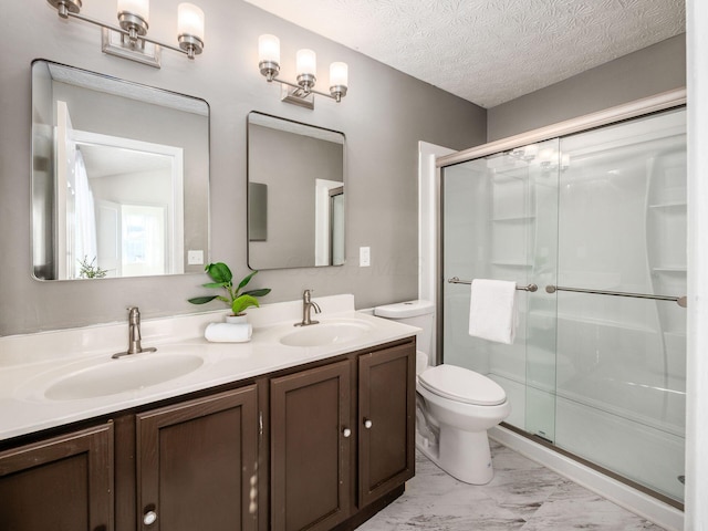 bathroom with toilet, a shower with door, vanity, and a textured ceiling