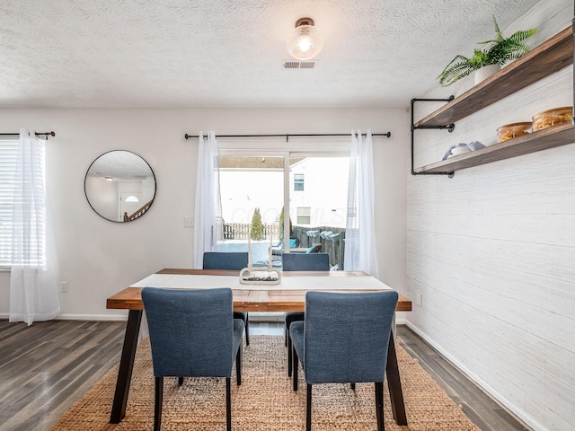 dining area featuring a wealth of natural light, a textured ceiling, and dark hardwood / wood-style flooring