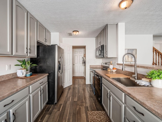 kitchen with sink, dark wood-type flooring, gray cabinetry, and appliances with stainless steel finishes