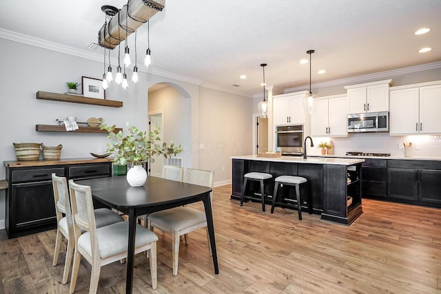 dining room with crown molding, light hardwood / wood-style flooring, and sink