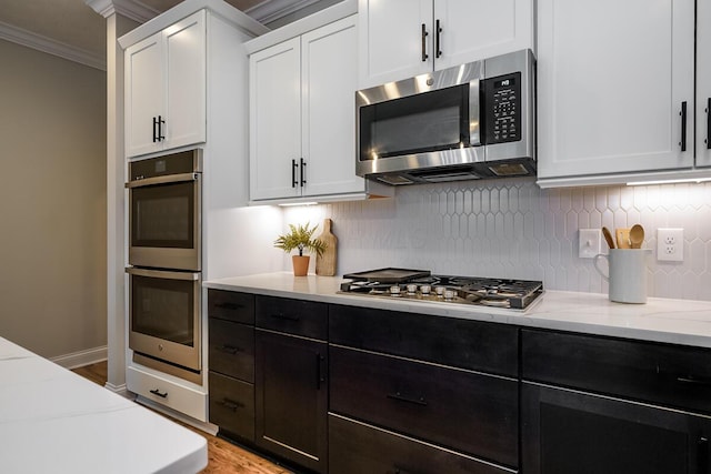 kitchen featuring backsplash, stainless steel appliances, white cabinetry, and light stone counters