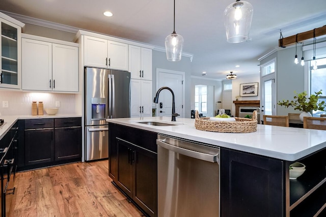 kitchen with appliances with stainless steel finishes, a center island with sink, white cabinetry, and sink