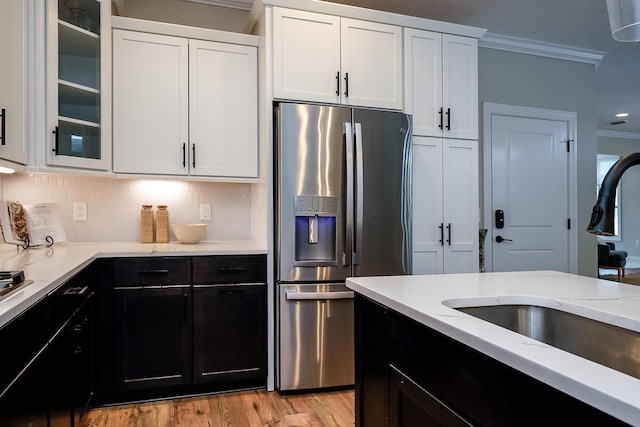 kitchen featuring light wood-type flooring, ornamental molding, sink, stainless steel fridge with ice dispenser, and white cabinetry