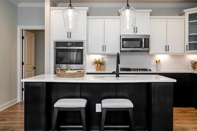 kitchen featuring backsplash, stainless steel appliances, sink, a center island with sink, and white cabinets