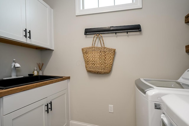 laundry area featuring washer and dryer, cabinets, and sink