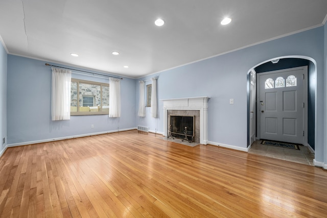 unfurnished living room featuring a fireplace, light hardwood / wood-style floors, and crown molding