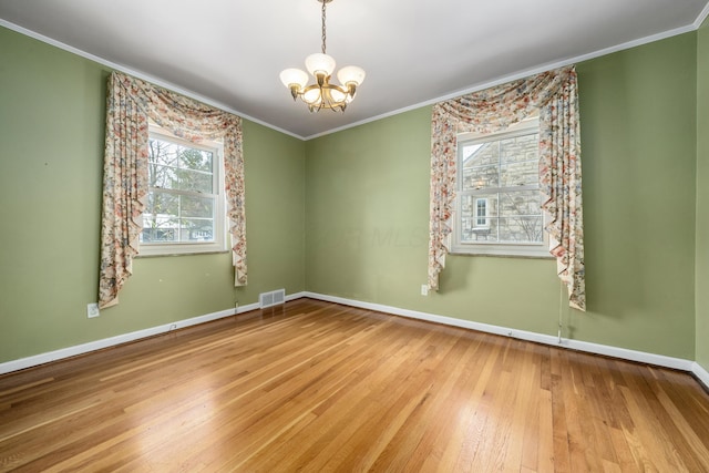 spare room with ornamental molding, light hardwood / wood-style floors, and a notable chandelier