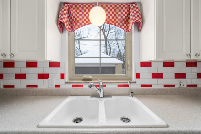 kitchen featuring white cabinetry, decorative backsplash, sink, and hanging light fixtures