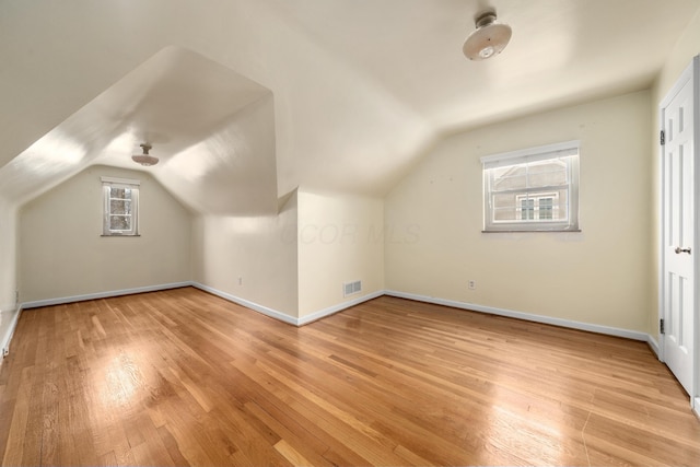 additional living space with light hardwood / wood-style flooring and lofted ceiling