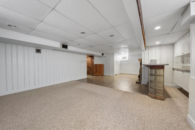 basement with a paneled ceiling and light carpet