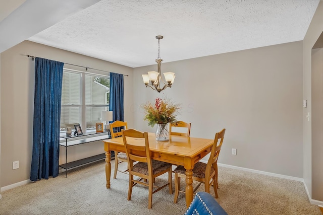 carpeted dining room featuring a chandelier and a textured ceiling