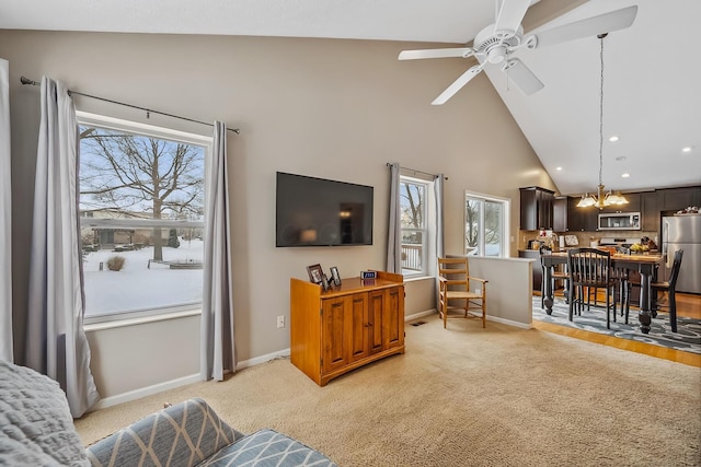 living room featuring ceiling fan with notable chandelier, light colored carpet, and high vaulted ceiling