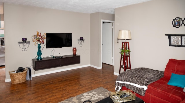 living room featuring dark wood-type flooring and a textured ceiling