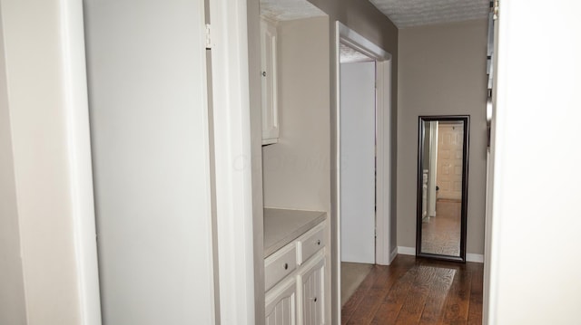 hallway with a textured ceiling and dark hardwood / wood-style floors