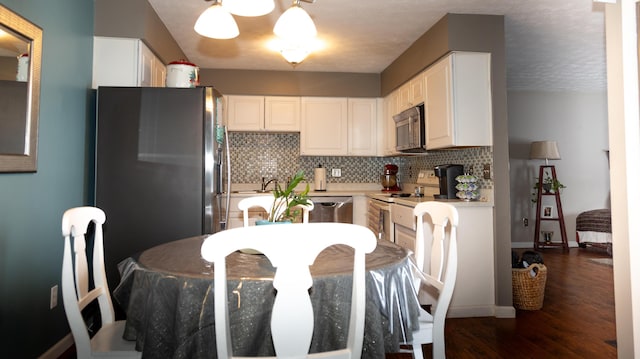 kitchen with decorative backsplash, dark hardwood / wood-style flooring, dishwasher, and white cabinetry