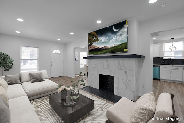 living room with a tile fireplace, light wood-type flooring, and sink