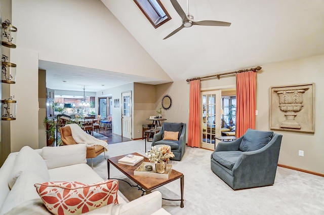 living room featuring carpet flooring, a skylight, ceiling fan, and high vaulted ceiling