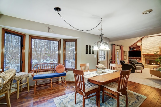 dining space featuring a notable chandelier, a fireplace, and dark wood-type flooring