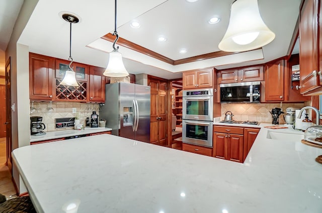 kitchen with pendant lighting, crown molding, appliances with stainless steel finishes, tasteful backsplash, and a tray ceiling