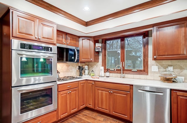 kitchen featuring backsplash, sink, stainless steel appliances, and ornamental molding