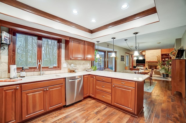 kitchen featuring dishwasher, sink, hanging light fixtures, kitchen peninsula, and crown molding