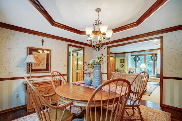 dining room with hardwood / wood-style flooring, a raised ceiling, crown molding, and a chandelier