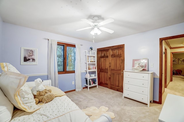 bedroom featuring ceiling fan, ornamental molding, light carpet, and a closet