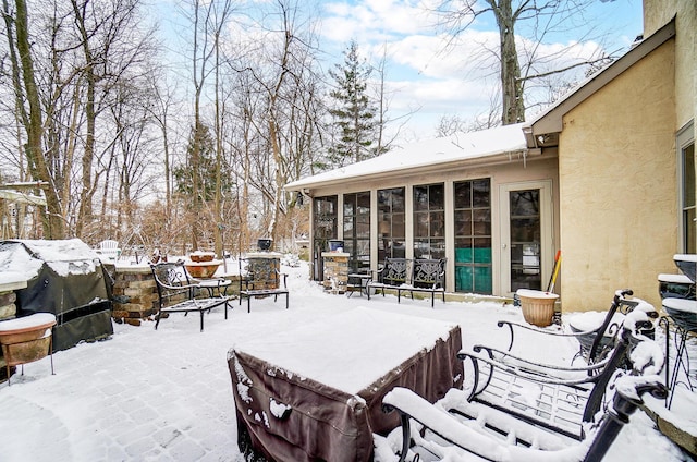 snow covered deck with a grill and a sunroom