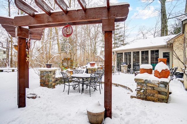 snow covered patio featuring a sunroom