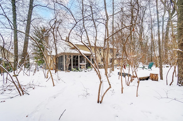 yard layered in snow featuring a sunroom