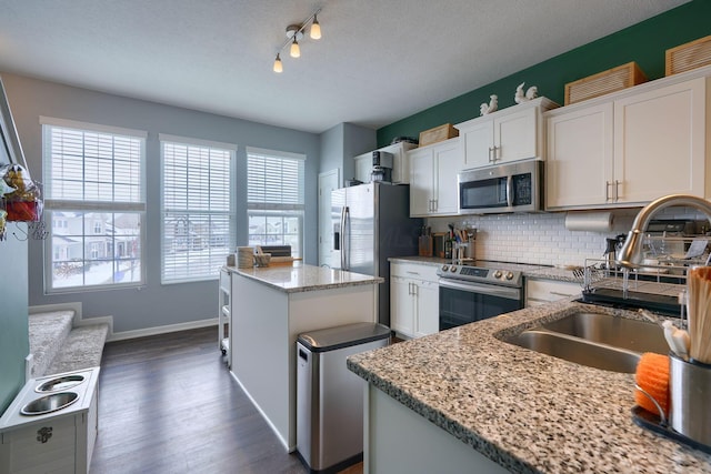 kitchen with white cabinetry, a center island, light stone counters, and appliances with stainless steel finishes