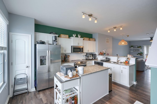 kitchen featuring white cabinetry, kitchen peninsula, decorative light fixtures, a kitchen island, and appliances with stainless steel finishes