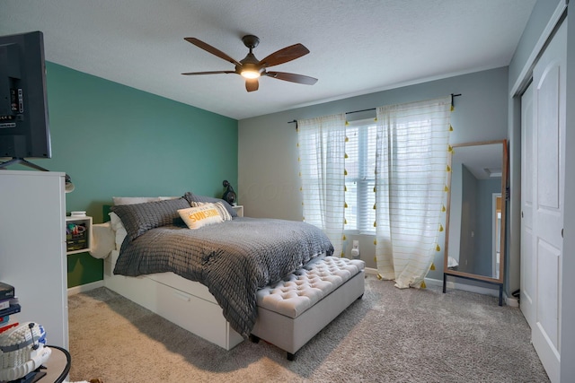 bedroom with a textured ceiling, carpet floors, a closet, and ceiling fan