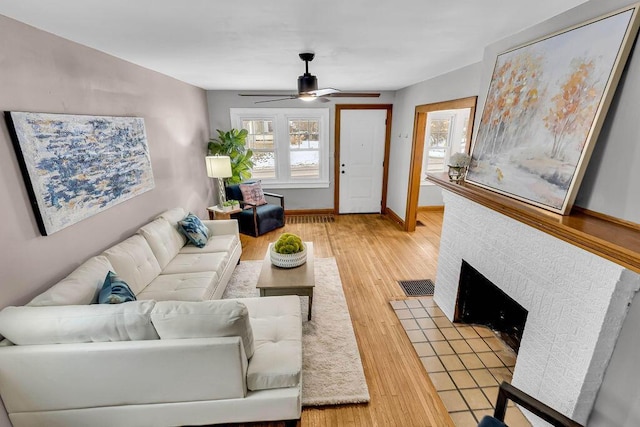 living room with ceiling fan, wood-type flooring, and a fireplace