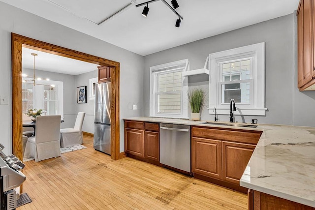 kitchen featuring an inviting chandelier, sink, hanging light fixtures, light hardwood / wood-style floors, and stainless steel appliances