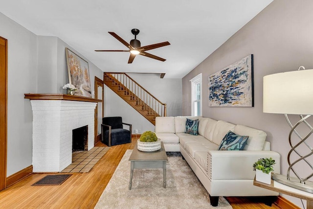 living room with ceiling fan, a fireplace, and wood-type flooring