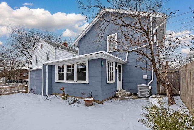 snow covered house featuring central air condition unit