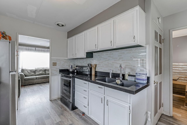 kitchen featuring refrigerator, white cabinetry, sink, and black electric range