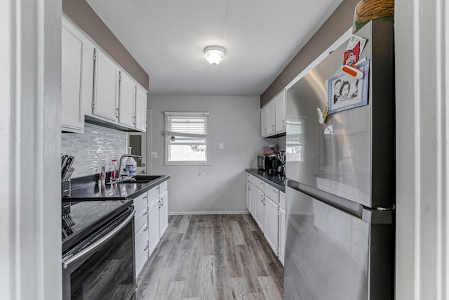 kitchen with white cabinetry, stainless steel fridge, black electric range, and sink