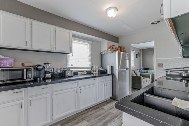 kitchen featuring tasteful backsplash, stainless steel refrigerator, white cabinetry, and light hardwood / wood-style floors