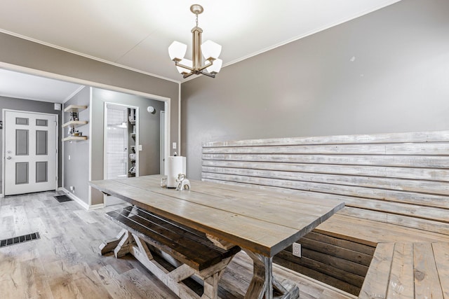 dining room featuring light wood-type flooring, an inviting chandelier, and ornamental molding