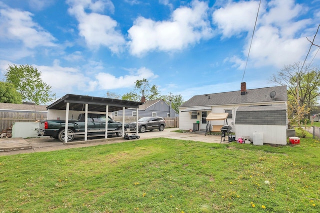 rear view of property with a carport and a yard