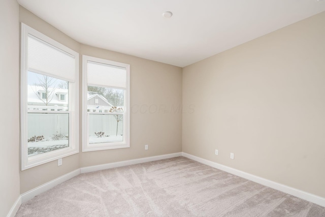 unfurnished room featuring baseboards and light colored carpet