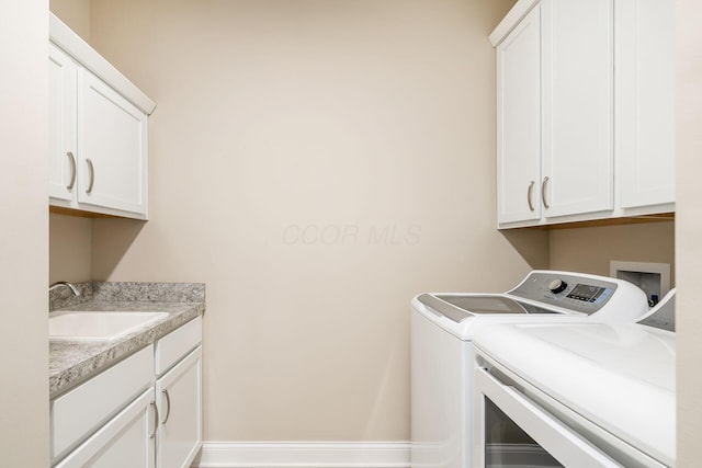 clothes washing area with a sink, washing machine and clothes dryer, and cabinet space