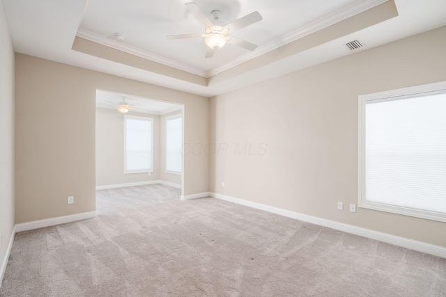 empty room featuring a raised ceiling, visible vents, and crown molding