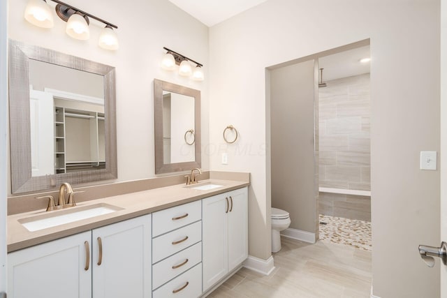 bathroom featuring a sink, a tile shower, and double vanity