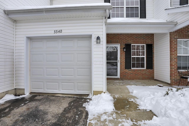 snow covered property entrance with a garage